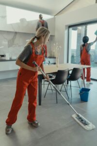 pexels photo 6197116 6197116 Cleaning team in red overalls mopping and sanitizing a modern home interior.